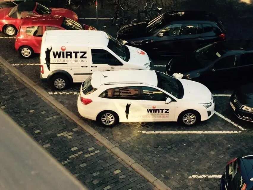 Zwei WIRTZ-Firmenwagen auf einem Parkplatz.