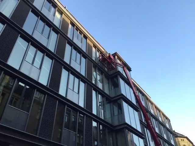 Glasreinigung an einem mehrgeschossigen Gebäude mit Teleskopstange.