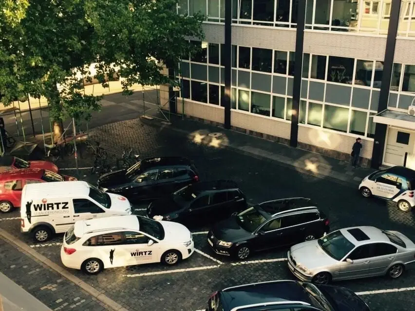 WIRTZ-Firmenwagen auf einem Parkplatz vor Bürogebäuden.
