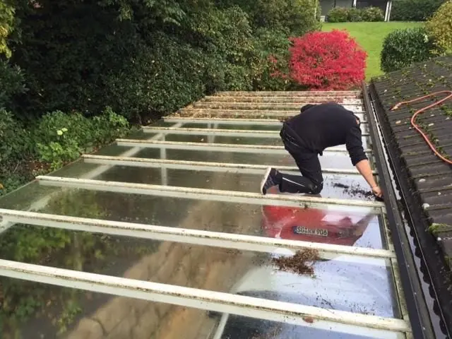 Mitarbeiter reinigt die Glasflächen eines Wintergartendachs.