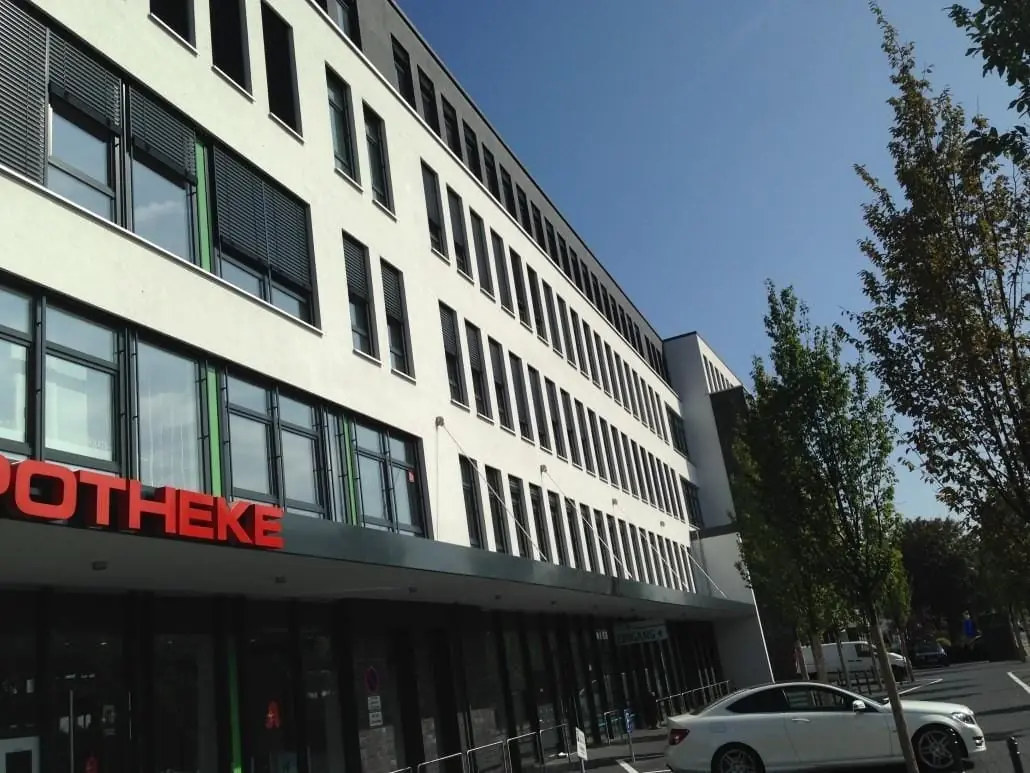 Geschäftshaus mit Apotheke und langen Fensterbändern.