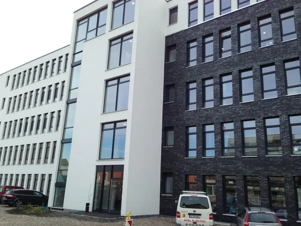 Zwei moderne Bürogebäude mit heller und dunkler Fassade.