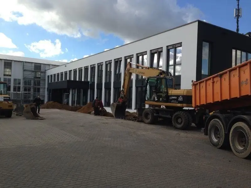 Flaches Bürogebäude mit Baustelle im Vordergrund.
