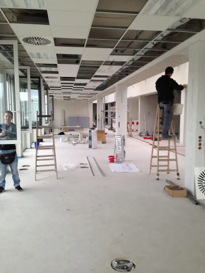 Baureinigung in einem langen Flur mit Leitern.