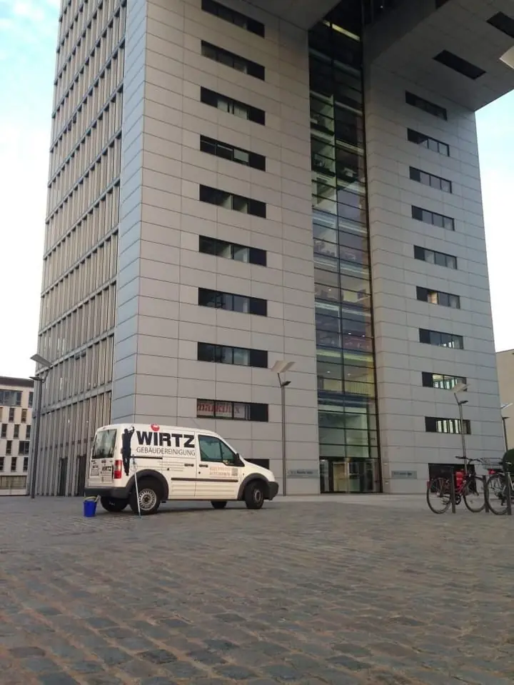 Hochhaus mit WIRTZ-Firmenwagen davor.