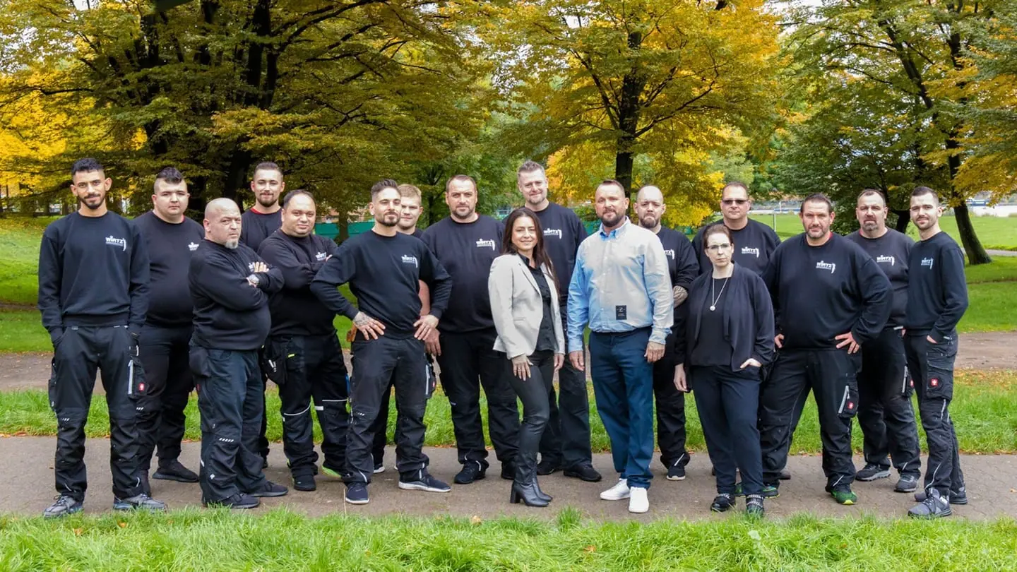 Das WIRTZ-Team in Arbeitskleidung im herbstlichen Park.