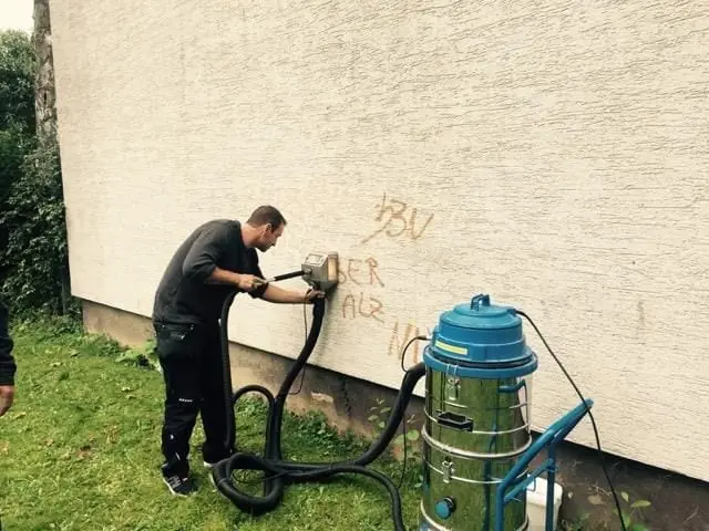 Mitarbeiter entfernt das Graffiti mit Spezialgerät.