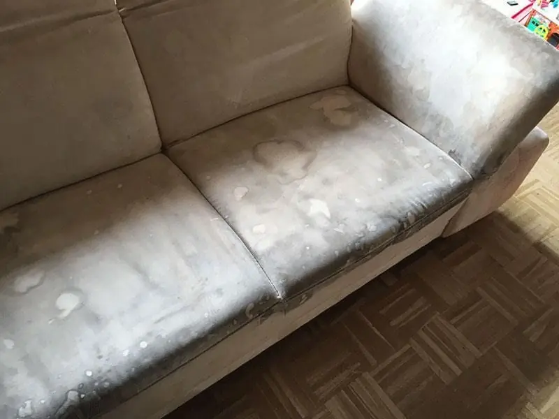 Helles Sofa mit vielen Flecken vor der Polsterreinigung.